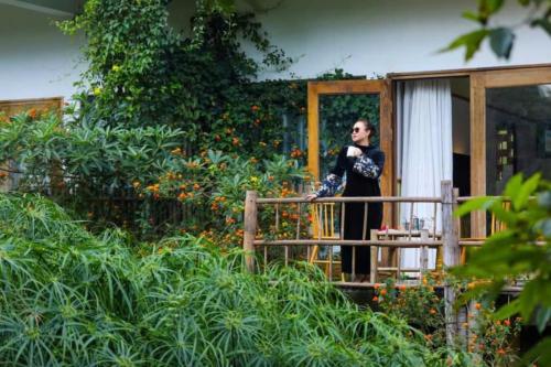 a woman standing on a balcony talking on a cell phone at Bakhan Village Resort in Mai Chau