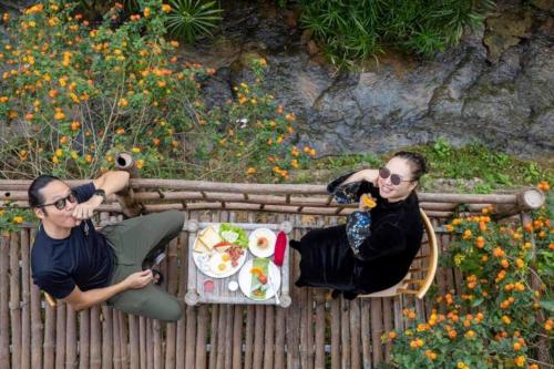 two men sitting at a table with a plate of food at Bakhan Village Resort in Mai Chau