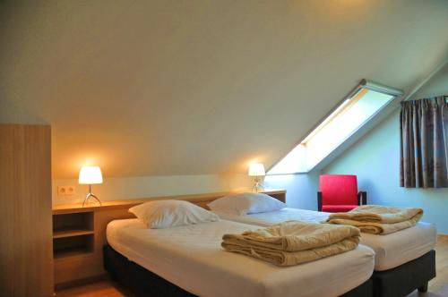 1 dormitorio con 2 camas, ventana y silla roja en La Coline, en Somme-Leuze