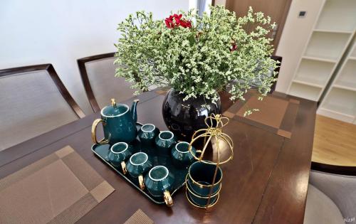 a table with a vase of flowers and tea cups at Investland- Vinhomes Metropolis one, two, three, four bedrooms in Hanoi
