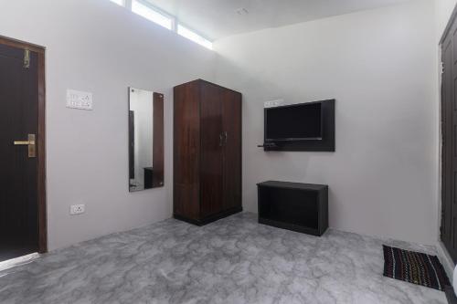 a room with a flat screen tv and a cabinet at Hotel O Pillars House in Shillong