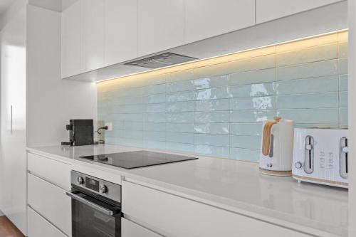 a white kitchen with a stove and a microwave at Pacific Breeze in Caves Beach