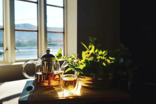a tea kettle and glasses on a table with a window at OAH 1870 Oldest Alesund House in Ålesund