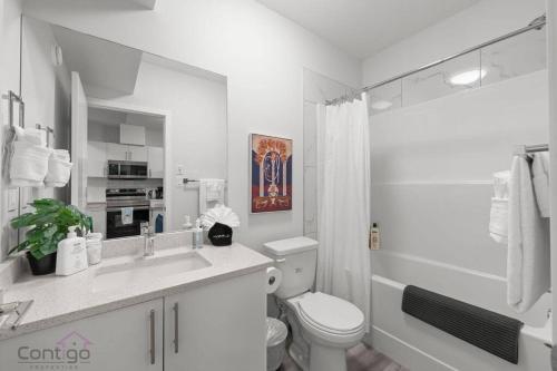 a white bathroom with a toilet and a sink at The Den, Centrally Located Suite, King Bed, WiFi! in Edmonton