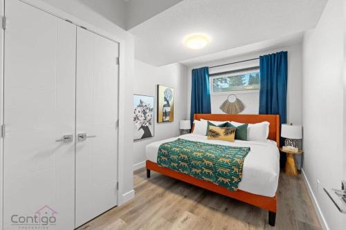 a bedroom with a large bed with blue curtains at The Den, Centrally Located Suite, King Bed, WiFi! in Edmonton