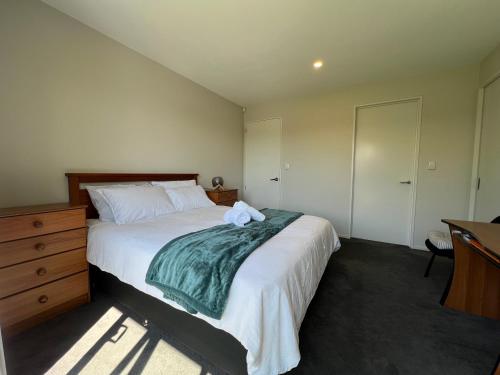 a bedroom with a large bed and a dresser at Wigram sunny quiet home in Christchurch