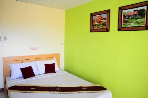 una camera da letto con una parete verde con un letto di Choktawee Smile a Chiang Mai