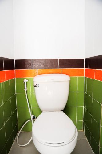 a toilet in a bathroom with green and colorful tiles at Choktawee Smile in Chiang Mai