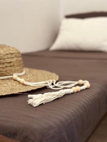 a straw hat and a necklace on a bed at Santino Mirissa in Mirissa