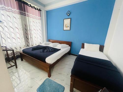 two beds in a small room with blue walls at 240 - Two forty in Bandarawela