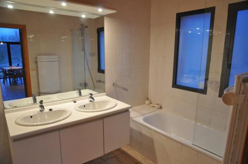ein Badezimmer mit zwei Waschbecken, einer Badewanne und einem Fenster in der Unterkunft Jardins de Ourthe 16 in Houffalize