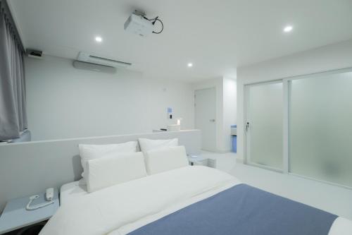 a white bedroom with a bed and a mirror at Aank Air Hotel Jinjuseong in Jinju