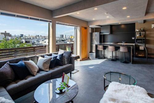 a living room with a couch and a view of a city at Harukazesou Tengachaya 160平米一戸建貸切 最大18名様 大浴場 駐車場3台 ウッドデッキ 電動自転車付 in Osaka