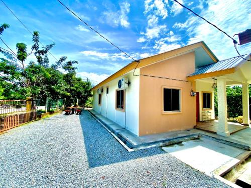 a small house sitting on top of a gravel road at Raees Homestay in Kampong Tanjong Minyak