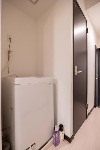 a white refrigerator in a room with a door at Asakusa Good Place Unmanned Hotel in Tokyo