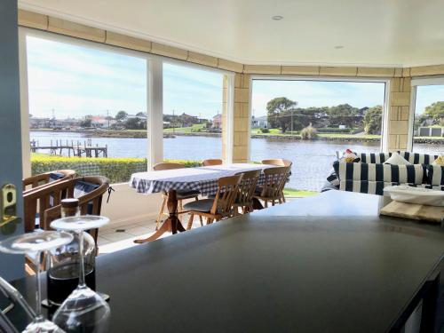 a living room with a table and a view of the water at Douglas Riverside in Port Fairy