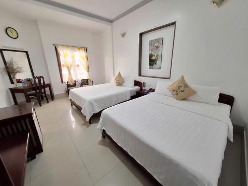 a bedroom with two beds and a table and chairs at Du Hung 2 Hotel in Ha Tien
