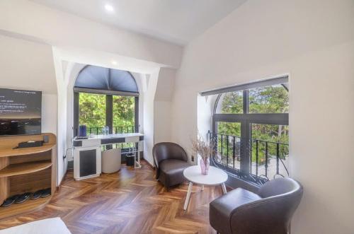 a living room with two chairs and a table and two windows at TP Dalat Hotel in Da Lat