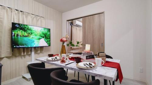 a dining room with a table and a tv on a wall at Residential Hotel GRAN梅香 Newly opened Hotel Baika Family friendly Free parking 10 minutes to USJ in Osaka