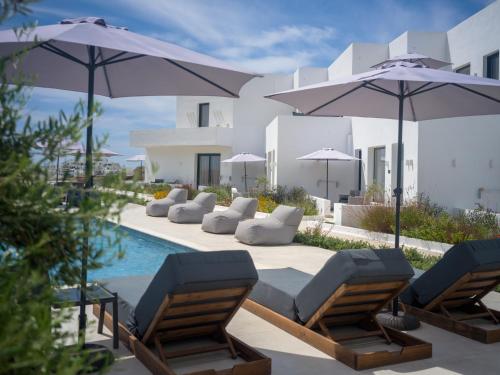 a pool with chairs and umbrellas next to a building at El Mar Naxos in Naxos Chora