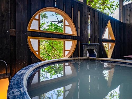 a swimming pool with circular windows in a wooden building at Nagominoyado Hanagokoro - Reopening in Mar 2024 in Hakone