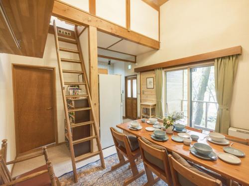 a dining room with a table and chairs and a ladder at Cottage Snowhills Hakuba in Hakuba