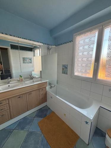 une salle de bain avec une baignoire, un lavabo et un miroir dans l'établissement Maison 3 chambres 1km de plage, à Six-Fours-les-Plages