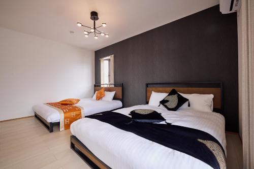 a bedroom with two beds with white sheets at Fuji Holiday in Fujiyoshida