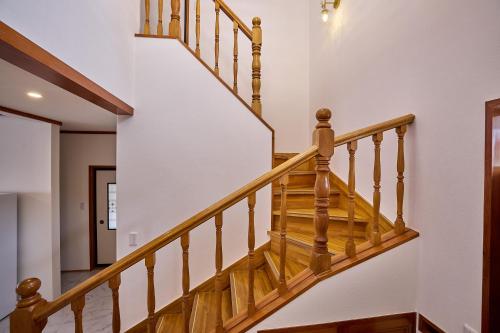 a staircase in a home with white walls and wooden railings at Fuji Holiday in Fujiyoshida