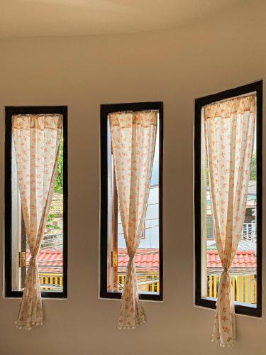 three windows with curtains in a room at DƯỚI TÁN CÂY homestay in Tây Ninh