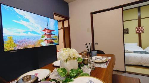 a room with a table with flowers and a tv at 402 Newly opened Hotel Baika Family friendly Free parking 10 minutes to USJ in Osaka