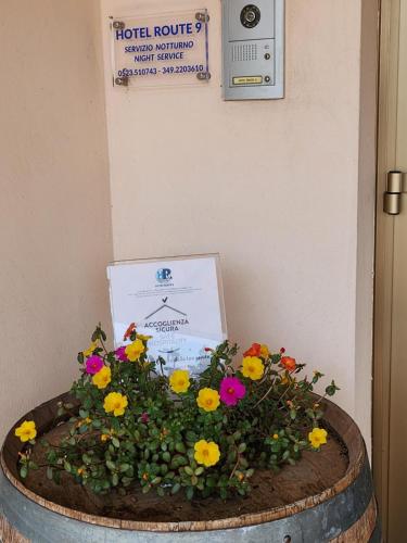 a flower arrangement in a barrel with a sign on the wall at Hotel Route 9 in Cadeo