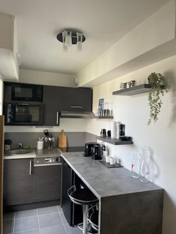 une cuisine avec des armoires noires et un comptoir dans l'établissement Appartement Touquet 's Times, à Le Touquet-Paris-Plage