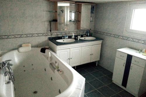 a bathroom with a tub and two sinks and a bath tub at Un spacieux et confortable châlet in Châtel-Saint-Denis