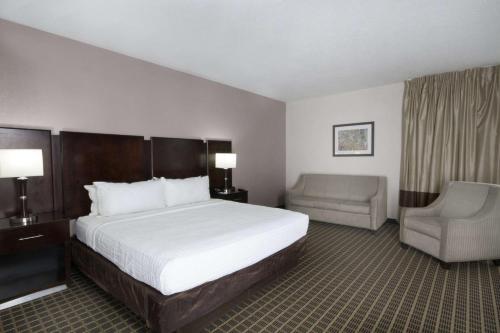 a hotel room with a bed and a chair at Clarion Inn & Suites Miami International Airport in Miami