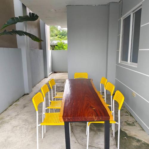 a wooden table and chairs with yellow chairs at Ada's Residential Villa La Union in Agoo