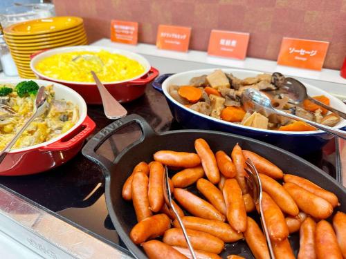 a table with bowls of food and a pan of carrots at Comfort Inn Zentsuji Inter in Marugame