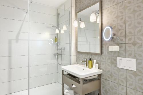 a white bathroom with a sink and a mirror at Hotel Rathauspark Wien, a member of Radisson Individuals in Vienna