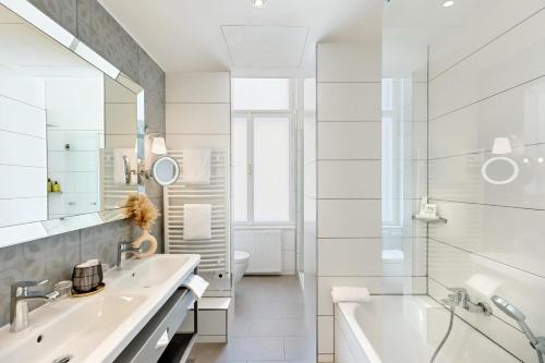 a white bathroom with a tub and a sink at Hotel Rathauspark Wien, a member of Radisson Individuals in Vienna