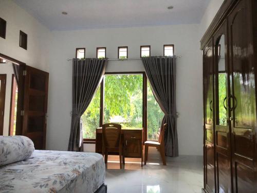 a bedroom with a bed and a desk and a window at Pondok Anugerah in Rantepao