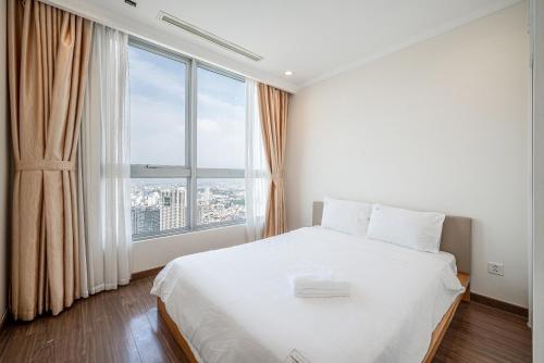 a bedroom with a white bed with a large window at Vinhomes Central Park Apartment- Landmark Luxury in Ho Chi Minh City