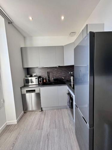 une cuisine avec des armoires blanches et un réfrigérateur en acier inoxydable dans l'établissement Les terrasses de Cap d Ail 2 - Vue Mer, à Cap d'Ail