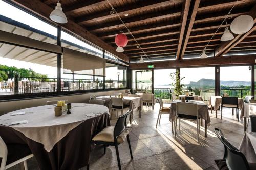un ristorante con tavoli, sedie e ampie finestre di Hotel Belvedere a Manerba del Garda