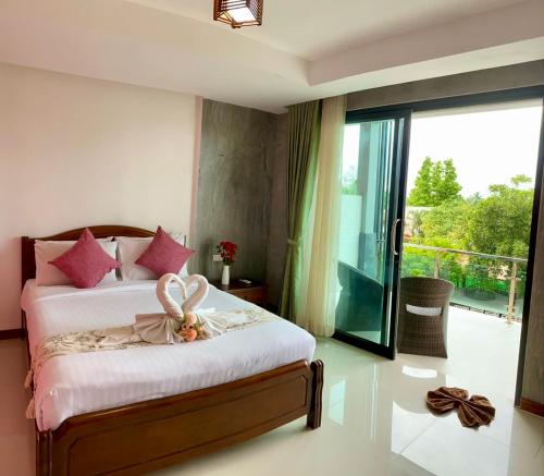 a bedroom with a bed with pink pillows and a balcony at Lanta Just Come Bungalow in Ko Lanta