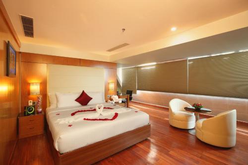 a bedroom with a large bed and two chairs at The Garuda Hotels in Trichūr