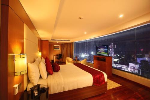 a hotel room with a bed and a large window at The Garuda Hotels in Trichūr