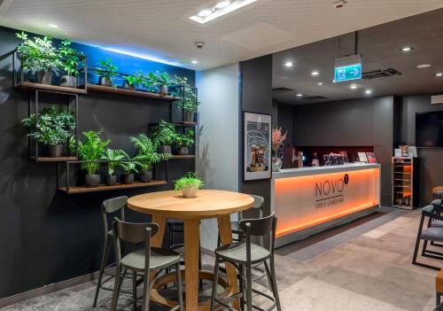 a cafe with a wooden table and chairs and plants at Novotel Kraków City West in Kraków