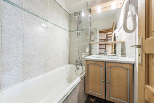 een badkamer met een bad, een wastafel en een douche bij Smartstay - Appartement cosy courchevel 1850 in Courchevel