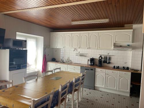 une cuisine avec des armoires blanches et une table en bois dans l'établissement Maison familiale à Picherande, à Picherande