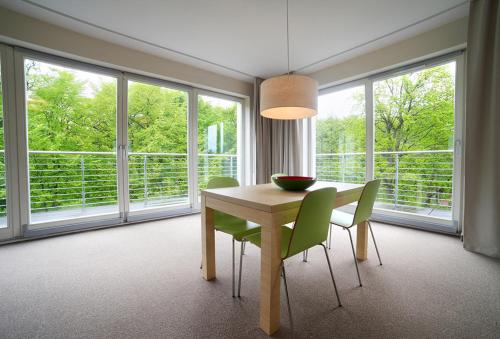 a dining room with a table and chairs and windows at Golden Tulip Międzyzdroje Residence in Międzyzdroje